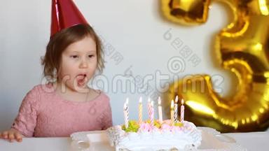 有趣的快乐孩子许愿，在聚会上吹灭<strong>生日蛋糕</strong>上的蜡烛。 可爱的<strong>小女孩</strong>戴着粉红色的帽子微笑着